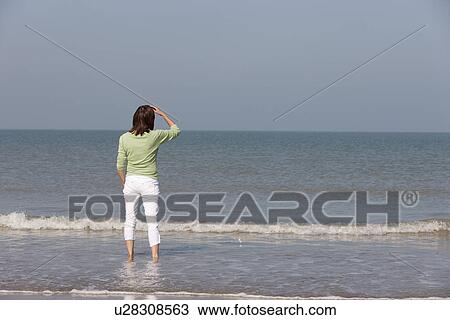 Woman on beach looking out to sea View Large Photo Image Stock Image - Woman on beach looking out to sea. Fotosearch