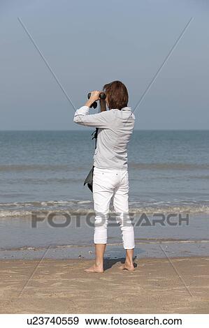 Woman on beach looking through binoculars View Large Photo Image Stock Photo - Woman on beach looking through binoculars. Fotosearch