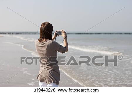 Woman on beach using camera View Large Photo Image Stock Photo - Woman on beach using camera. Fotosearch