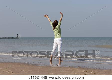 Woman on beach with arms raised View Large Photo Image Stock Photography - Woman on beach with arms raised. Fotosearch