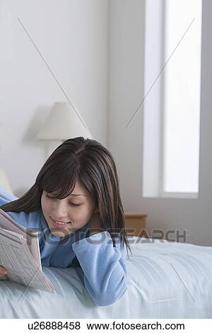 Woman reading newspaper in bed View Large Photo Image Stock Photo - Woman reading newspaper in bed. Fotosearch