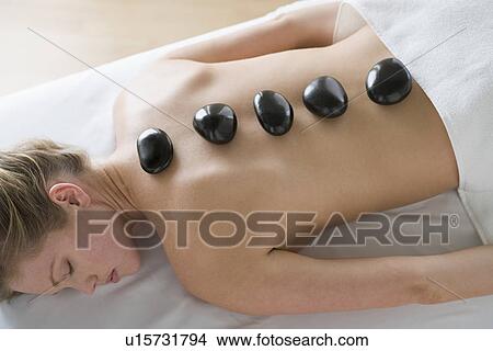 Picture - Woman receiving hot stone therapy. Fotosearch