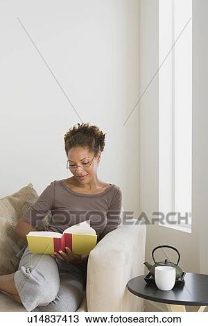 Stock Image - Woman relaxing with book at home. Fotosearch
