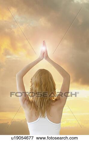 Stock Photo - Woman saluting sun in yoga gesture. Fotosearch
