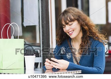 Woman sitting in sidewalk cafe and texting on mobile phone View Large Photo Image Stock Photography - Woman sitting in sidewalk cafe and texting on mobile phone. Fotosearch