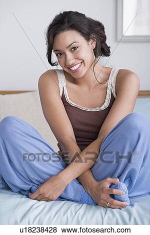 Stock Photo - Woman sitting on bed. Fotosearch