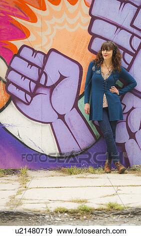 Woman standing against wall with graffiti View Large Photo Image Stock Photo - Woman standing against wall with graffiti. Fotosearch