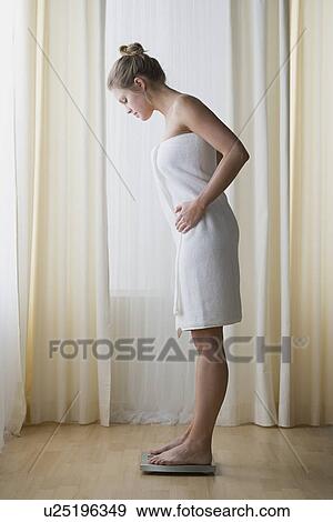 Stock Photo - Woman standing on weight scale. Fotosearch