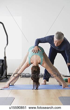 Woman stretching while instructor assisting her View Large Photo Image Stock Image - Woman stretching while instructor assisting her. Fotosearch