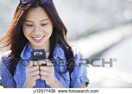 Woman text messaging outdoors View Large Photo Image Stock Photograph - Woman text messaging outdoors. Fotosearch