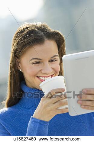 Woman using digital tablet and drinking coffee outdoors View Large Photo Image Stock Image - Woman using digital tablet and drinking coffee outdoors. Fotosearch