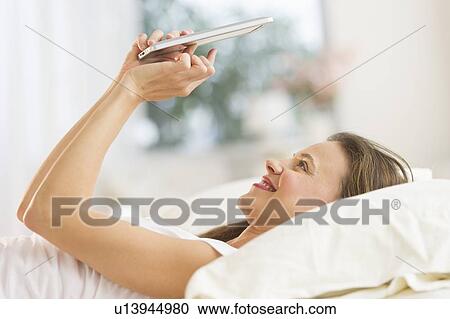 Woman using digital tablet in bed View Large Photo Image Stock Image - Woman using digital tablet in bed. Fotosearch