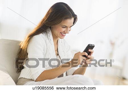 Stock Photograph - Woman using smart phone at home. Fotosearch