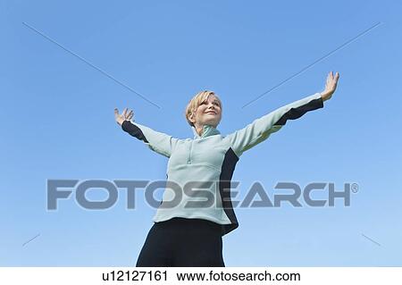 Woman with arms raised against blue sky View Large Photo Image Stock Image - Woman with arms raised against blue sky. Fotosearch