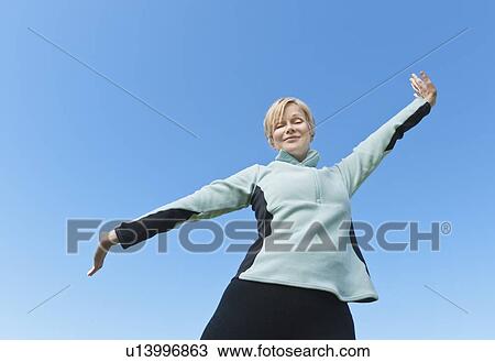 Woman with arms raised against blue sky View Large Photo Image Stock Image - Woman with arms raised against blue sky. Fotosearch