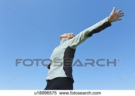Woman with arms raised against blue sky View Large Photo Image Stock Photography - Woman with arms raised against blue sky. Fotosearch