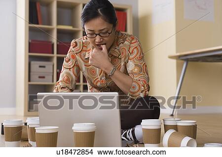 Woman working on laptop surrounded by empty coffee cups View Large Photo Image Picture - Woman working on laptop surrounded by empty coffee cups. Fotosearch