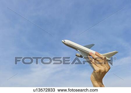 Stock Image - Woman's hand holding plane model. Fotosearch