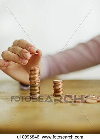 Woman's hand stacking coins, studio shot View Large Photo Image Stock Photograph - Woman's hand stacking coins, studio shot. Fotosearch