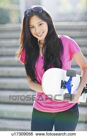 Stock Photograph - Young Asian woman posing with skateboard. Fotosearch