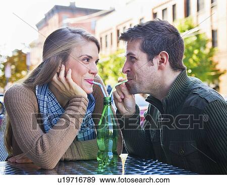 Young couple drinking from one bottle using straws View Large Photo Image Stock Photo - Young couple drinking from one bottle using straws. Fotosearch