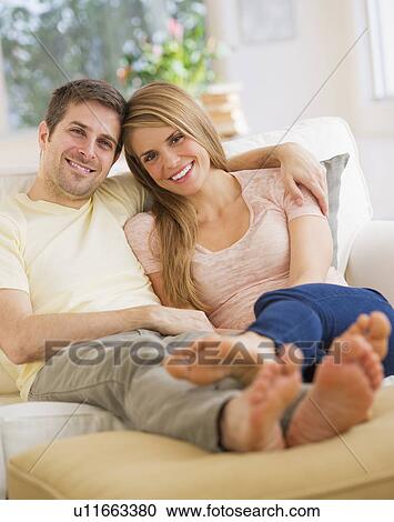 Young couple relaxing on sofa View Large Photo Image Stock Image - Young couple relaxing on sofa. Fotosearch