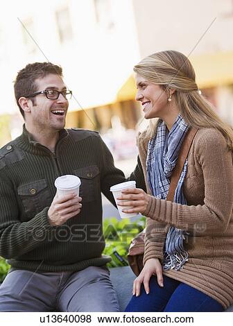 Young couple sitting with take-away coffee View Large Photo Image Stock Photo - Young couple sitting with take-away coffee. Fotosearch