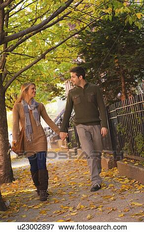 Stock Photo - Young couple walking on pavement. Fotosearch