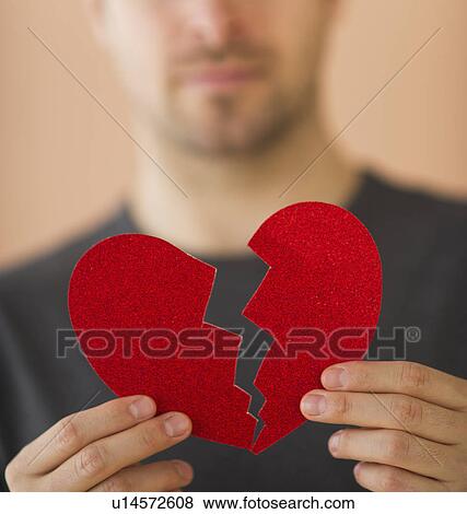 Stock Photo - Young man holding broken paper heart. Fotosearch