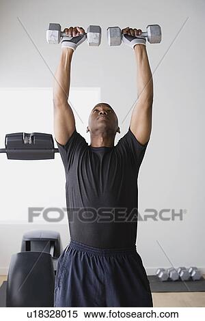 Young man lifting weights in gym View Large Photo Image Stock Photography - Young man lifting weights in gym. Fotosearch