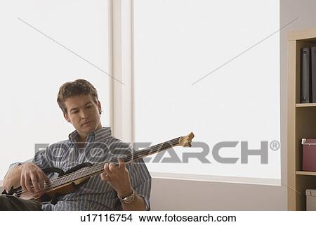 Young man playing electric base guitar View Large Photo Image Picture - Young man playing electric base guitar. Fotosearch