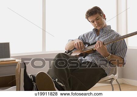 Young man playing electric base guitar View Large Photo Image Stock Photo - Young man playing electric base guitar. Fotosearch