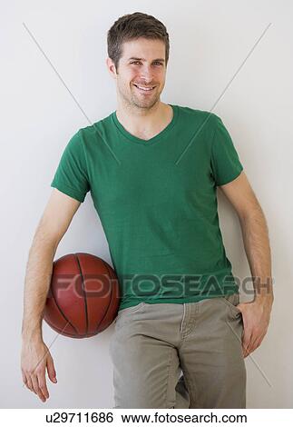 Young man standing with basket ball View Large Photo Image Stock Photograph - Young man standing with basket ball . Fotosearch