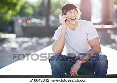 Young man using mobile phone outdoors View Large Photo Image Stock Image - Young man using mobile phone outdoors. Fotosearch