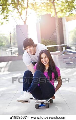 Young multi-racial couple playing with skateboard View Large Photo Image Picture - Young multi-racial couple playing with skateboard. Fotosearch