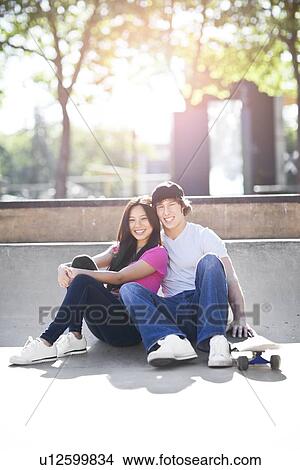 Young multi-racial couple posing with skateboard View Large Photo Image Picture - Young multi-racial couple posing with skateboard. Fotosearch