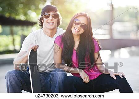 Young multi-racial couple posing with skateboard View Large Photo Image Stock Image - Young multi-racial couple posing with skateboard. Fotosearch