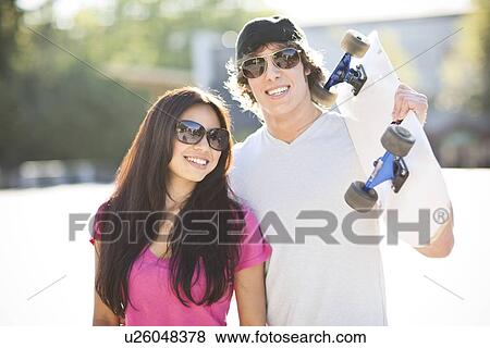 Young multi-racial couple posing with skateboard View Large Photo Image Stock Photo - Young multi-racial couple posing with skateboard. Fotosearch
