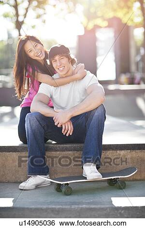 Stock Photograph - Young multi-racial couple posing with skateboard. Fotosearch