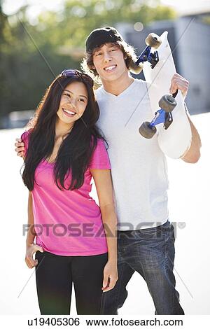 Young multi-racial couple posing with skateboard View Large Photo Image Stock Photograph - Young multi-racial couple posing with skateboard. Fotosearch