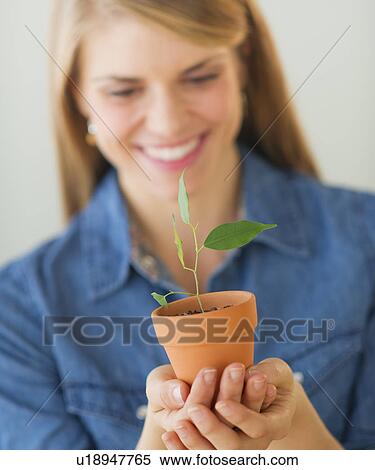 Young woman holding small plant View Large Photo Image Stock Photography - Young woman holding small plant. Fotosearch