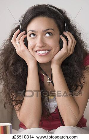 Young woman listening to music and smiling View Large Photo Image Picture - Young woman listening to music and smiling. Fotosearch
