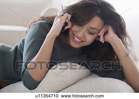 Young woman lying on sofa and talking on mobile phone View Large Photo Image Stock Image - Young woman lying on sofa and talking on mobile phone. Fotosearch