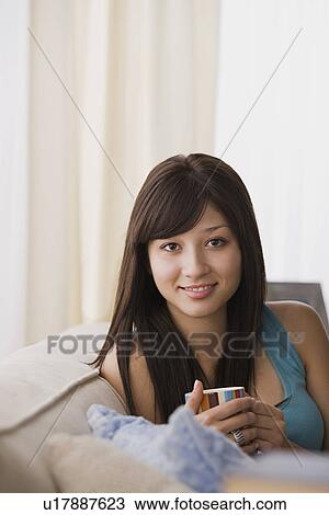 Stock Image - Young woman relaxing on sofa. Fotosearch