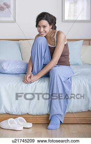 Stock Photo - Young woman sitting on bed. Fotosearch