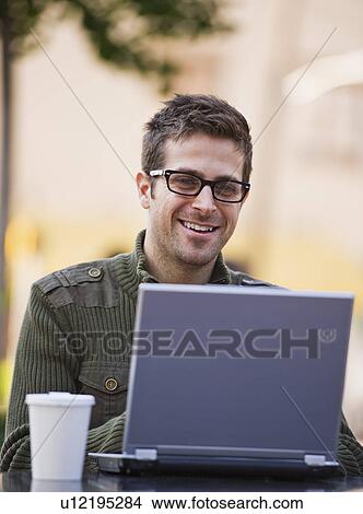 Young woman sitting with laptop in sidewalk cafe View Large Photo Image Picture - Young woman sitting with laptop in sidewalk cafe. Fotosearch
