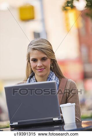 Young woman sitting with laptop in sidewalk cafe View Large Photo Image Stock Photography - Young woman sitting with laptop in sidewalk cafe. Fotosearch