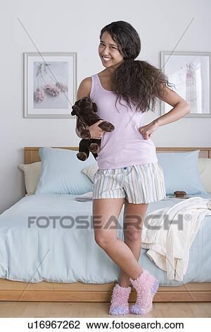 Stock Image - Young woman standing in bedroom. Fotosearch