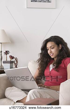 Picture - Young woman using laptop at home. Fotosearch