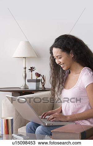 Young woman using laptop at home View Large Photo Image Stock Image - Young woman using laptop at home. Fotosearch